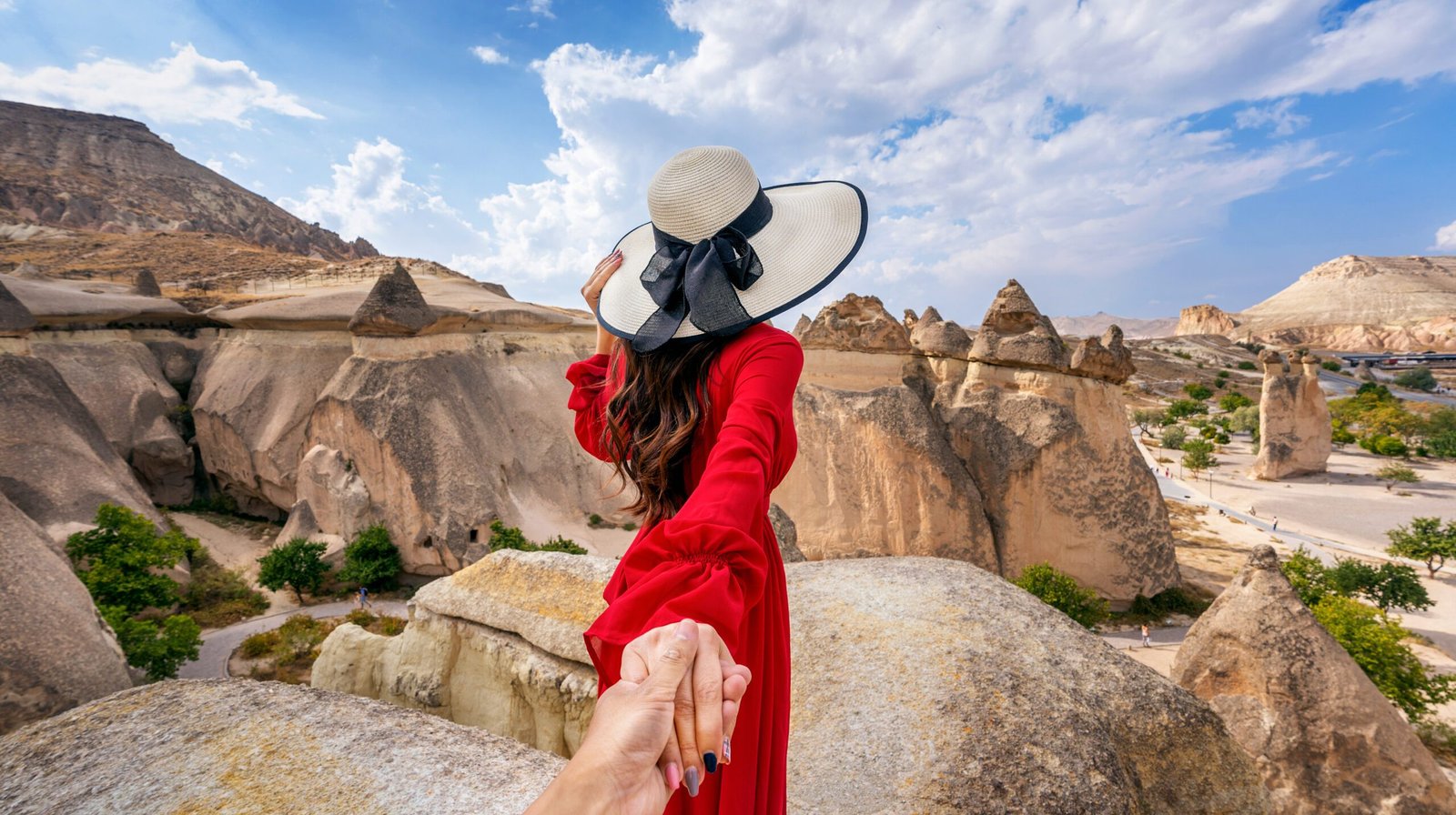 Women tourists holding man's hand and leading him to Fairy Chimneys in Cappadocia, Turkey.
